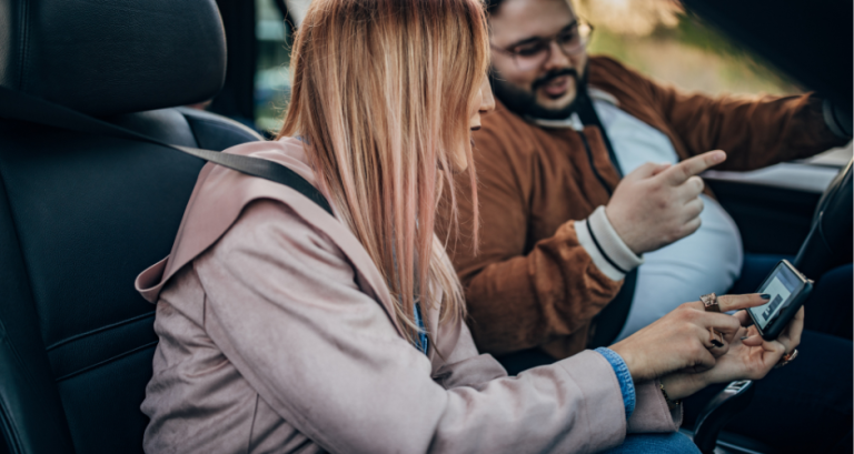 A man and woman in the car working with their telematics driving device,