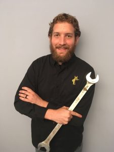 Andrew Schneider, owner of Bear Car Care, holding a comically giant, but useful, wrench.